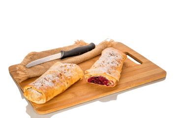 One cherry strudel with ceramic dishes on a bamboo kitchen board, close-up, isolated on a white background.