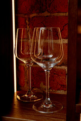 Wine glasses made of thin glass against a red brick background, with lighting. Glasses at the bar.