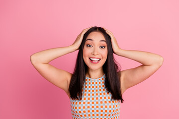 Charming young woman with a cheerful smile posing against a bright pink backdrop, styled in a trendy summer outfit