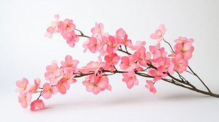 Fototapeta premium Delicate pink artificial flowers branch on a white background ideal for home decor and floral arrangements