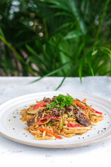 A savory udon noodle dish with stir-fried beef, colorful bell peppers, and zucchini.