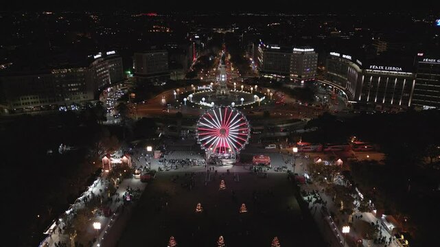 Aerial drone view of revellers at Wonderland Lisbon Christmas decorations at Eduardo XII Park featuring a large ferris wheel and themed shops