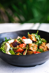 Close-up of a vibrant salad with roasted eggplant, creamy feta cheese, tomatoes, and fresh arugula.