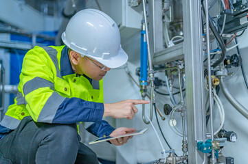 Asian electric engineer holding clipboard for checking and monitoring the electrical system in the control room,Technician thailand people working