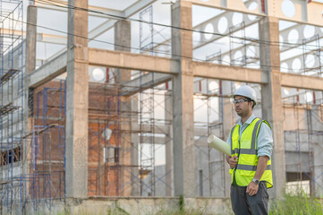 Fototapeta premium Two Asian engineer working at site of a large building project,Work overtime at construction site,Team of engineer discus at site,The architect, supervisor, and foreman meet to discuss the design