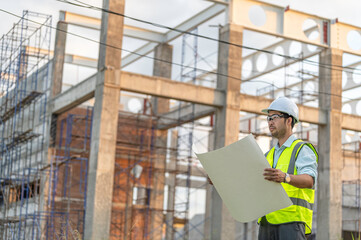 Fototapeta premium Two Asian engineer working at site of a large building project,Work overtime at construction site,Team of engineer discus at site,The architect, supervisor, and foreman meet to discuss the design