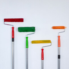 A vertical set of colorful paint rollers with ergonomic handles on a white background. Perfect for...