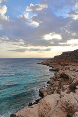 Rocky coast against the backdrop of a beautiful sunset. Cape Greco peninsula, Cyprus 