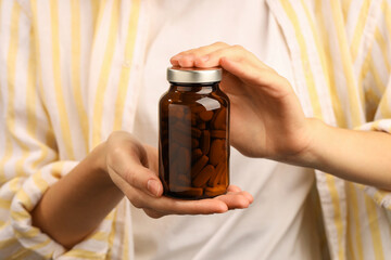 Woman holding medical bottle with pills, closeup
