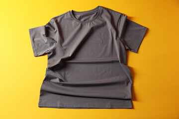 One t-shirt on yellow background, top view