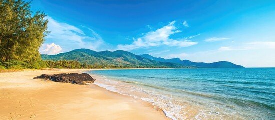 Obraz premium Scenic beach landscape with mountains under a clear sky ideal for travel and vacation photography