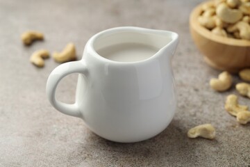 Fresh cashew milk and nuts on grey textured table, closeup