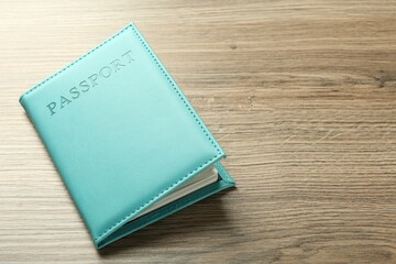 Passport in turquoise cover on wooden table, space for text