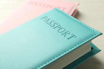 Two passports in bright covers on white wooden table, closeup