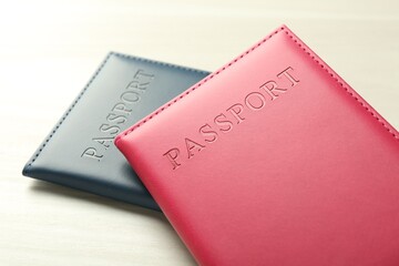 Two passports in bright covers on white wooden table, closeup