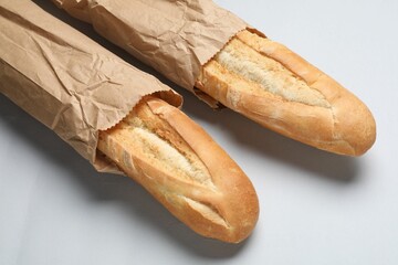 Paper bags with fresh baguettes on white background, closeup