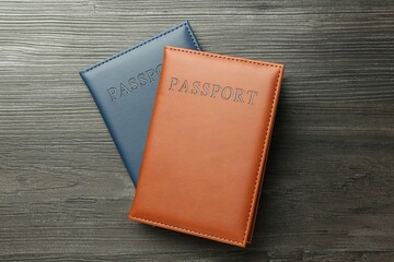 Passports in color covers on wooden table, top view