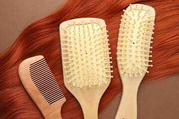 Brushes, comb and lock of hair on brown background, flat lay