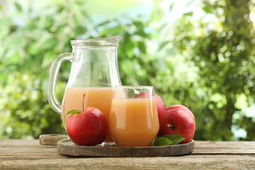 Tasty apple juice and fresh fruits on wooden table against blurred background