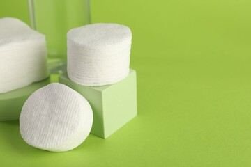 Clean cotton pads on green background, closeup. Space for text
