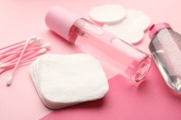 Cotton pads, swabs and cosmetic products on pink background, closeup