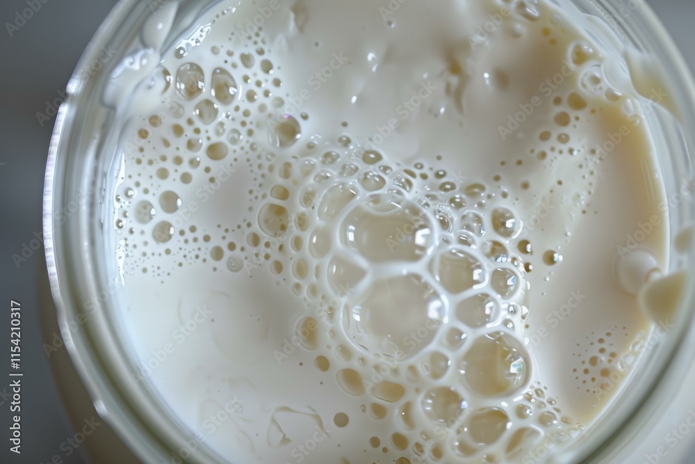 Poster close up of milk with bubbles forming intricate patterns inside a glass jar, creating a visually app
