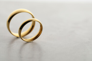 Beautiful golden wedding rings on gray background, closeup. Space for text