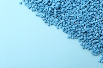 Pile of plastic granules on light blue background, top view. Space for text