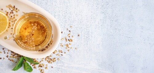 Glass cup of buckwheat tea, mint and lemon on light background with space for text, top view