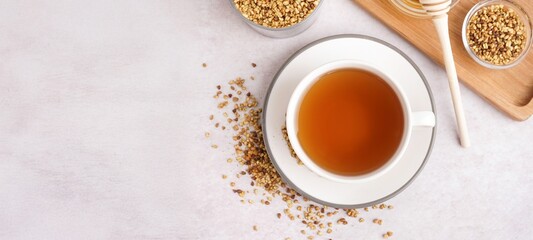 Cup of tasty buckwheat tea on light background with space for text, top view