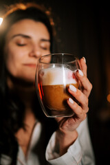 Woman Enjoys Cappuccino With Marshmallows While Relaxing in Bed Surrounded by Festive Christmas Decorations