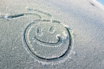 Snow happy face on the car window. Smile in the snow, happy cheerful image. winter