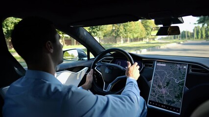 Successful businessman riding on electrical vehicle at city. Male entrepreneur driving a modern electric car at urban road. Businessperson operating auto at sunny day. Young man commuting to work