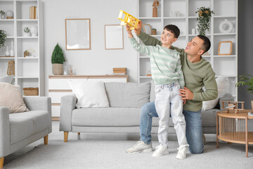 Fototapeta premium Cute little boy and his father playing with plane at home