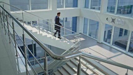 Businessman hurrying office stairs looking watch. Leader walking down staircase