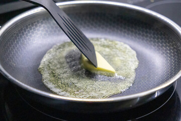 melting butter in a frying pan with a black spatula on a hot stovetop