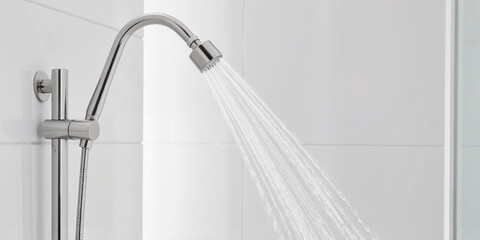 Shower head with water flow on a clean tiled background for a modern bathroom concept