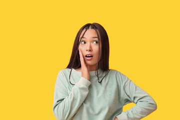 Fototapeta premium Shocked young Asian woman with stylish mint makeup on yellow background