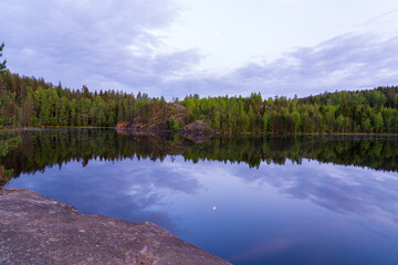 Fototapeta premium A forest lake with water like a mirror reflecting the forest and the sky.