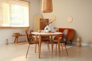 Table with hot tea, poppy buns, pampas grass and autumn leaves in living room