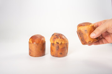 Mini panettone, mini panettone and human hand placed on white surface with white background, selective focus.