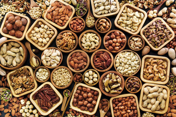 Colorful mix of various nuts: peanut and cashew, hazelnut and almond, pine nuts and walnut; healthy diet snack; vegan food background, selective focus, shallow focus