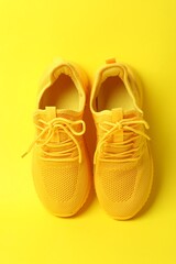 Pair of stylish sneakers on yellow background, above view