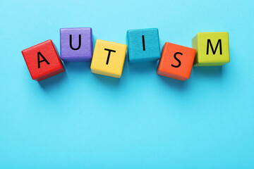 Word Autism made of colorful cubes on light blue background, top view. Space for text
