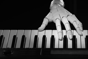 Artificial intelligence. Robot hand playing synthesizer on black background, closeup