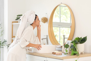 Beautiful young happy woman near mirror in bathroom