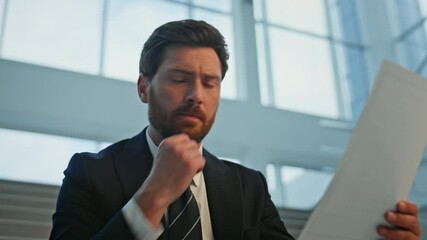 Serious ceo analyzing document dissatisfied information at office stairs closeup