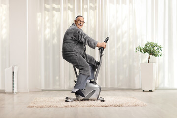Mature man in a bathrobe exercising on a stationary bike