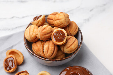 Bowl of sweet walnut shaped cookies with boiled condensed milk on white background