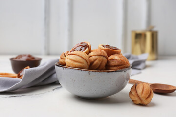 Bowl of sweet walnut shaped cookies with boiled condensed milk on white background